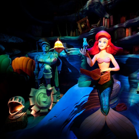 Un personaje de Audio-Animatronics de Ariel mira a través de un pequeño cofre de tesoros