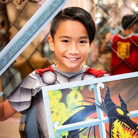 A boy with a knight makeover holding a sword and shield in Bibbidi Bobbidi Boutique