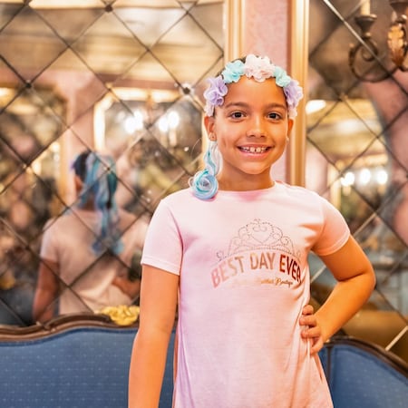 A girl with a flower headband, hair extension accessory and a Bibbidi Bobbidi Boutique T shirt
