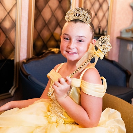A girl with a princess makeover holding a scepter in Bibbidi Bobbidi Boutique