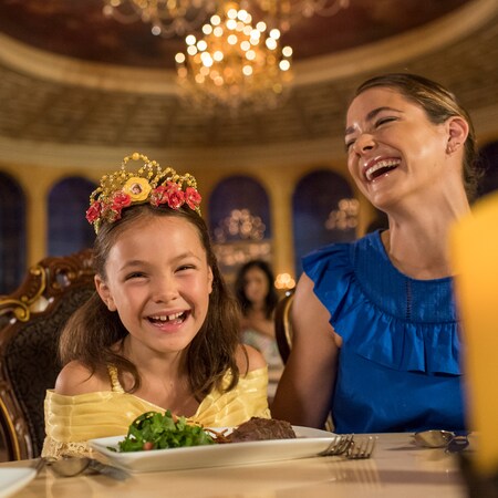 A young girl dressed as Belle dines with her parents at Be Our Guest Restaurant