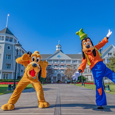 Pluto and Goofy posing for a photo on a walkway by Disney’s Yacht Club Resort