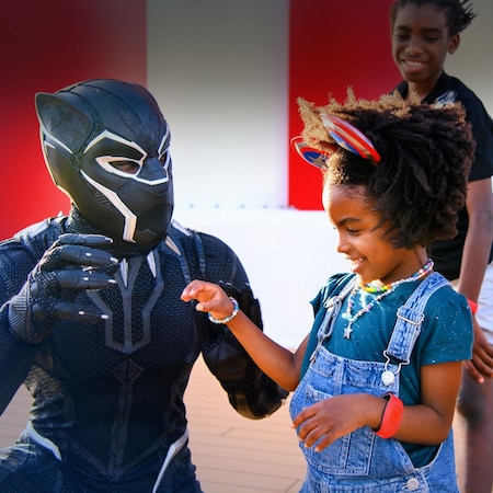 Black Panther showing a small girl how to flex her hand to look like claws while her father and sister watch in delight