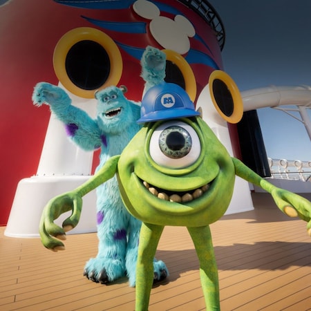Characters Mike and James from the Pixar movie Monsters Inc standing on the deck of a Disney cruise ship