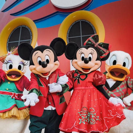 Mickey Mouse, Minnie Mouse, Pato Donald e Margarida vestidos com trajes natalinos posando juntos em um navio de cruzeiro da Disney 