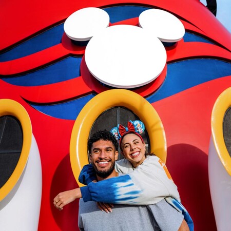 A couple poses in front of the funnel on a Disney Cruise Line ship