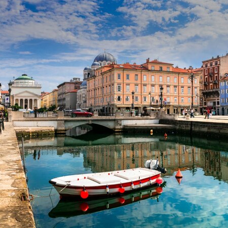 A small boat tied to a dock next to an outdoor café with umbrellas over each table