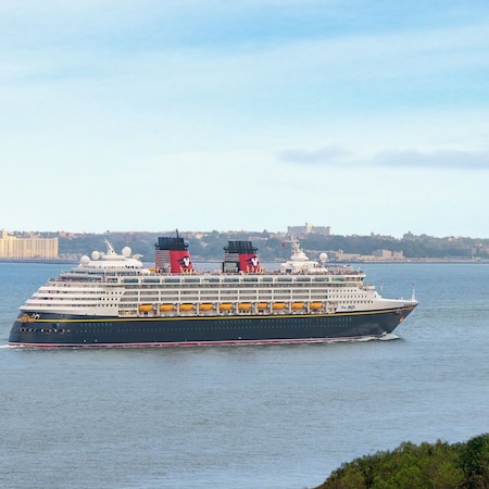 A Disney Cruise Line ship sails past the Statue of Liberty in New York Harbor