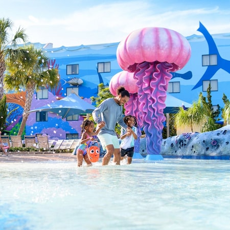 O pai brincando com suas duas filhas na piscina Big Blue Pool no Disney’s Art of Animation Resort 
