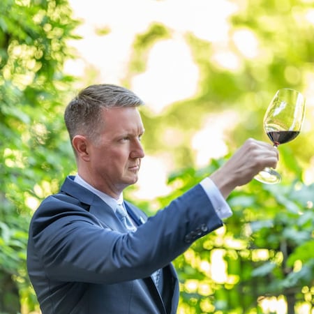 Sommelier Patrick Kirchen, Napa Rose's Wine Director inspecting a glass of wine