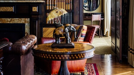 A living area with a couch, chair, side table and bookcase in the Adventure Land Suite at the Disneyland Hotel
