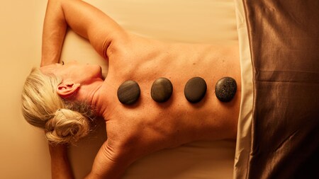 A woman enjoying a massage that incorporates heated river stones to help soothe and relax the body.