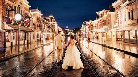 A bride and groom walk hand in hand down Main Street, U S A
