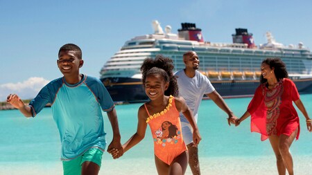 A boy and girl and their parents on a beach with a Disney cruise ship in the background