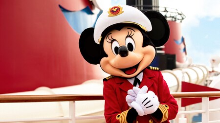 Minnie Mouse standing on deck of a cruise ship while wearing her captain's hat and outfit