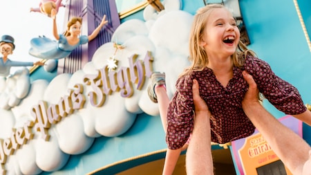 A happy little Guest is hoisted into the air as if she is flying in front of Peter Pans Flight