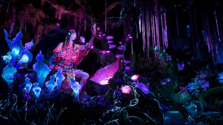 The Na’vi Shaman of Songs in a bioluminescent rainforest on the Na'vi River Journey attraction