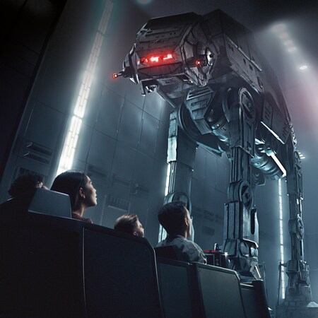 People in a transport vehicle inside a hanger bay look up at 2 towering AT-AT walkers
