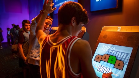 Two Guests high five while playing a touch screen trivia game