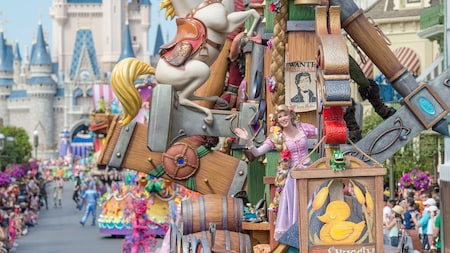 A parade in front of Cinderella Castle featuring Rapunzel on a float shaped like a boat and more characters following behind her