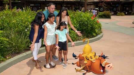 A family of 5 look at images of Simba, Timon and Pumbaa at the entrance of Animal Kingdom theme park