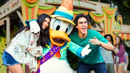 Un hombre y una mujer posan para una foto con Donald Duck en Donald’s Dino Bash.