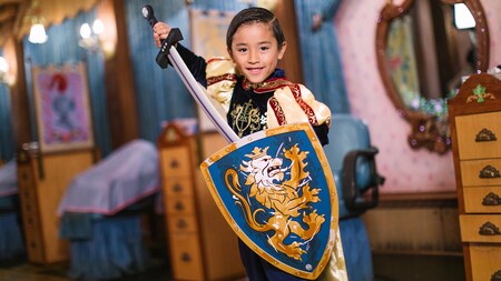 A young boy wearing a knight costume shows off his sword and shield