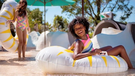 A girl smiles while sitting on a float at Disney’s Blizzard Beach water park	
