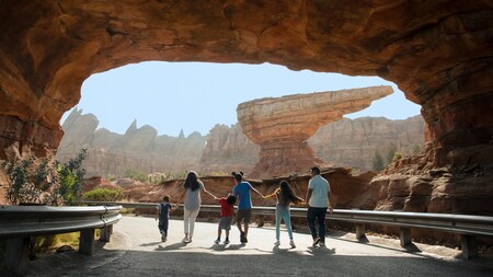 Una familia de seis camina de la mano por el paisaje rocoso de Radiator Springs