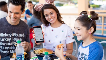 A parent displays a mobile order on an electronic device while her family eats