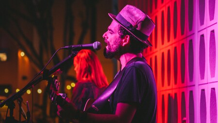 Musicians perform on a colorfully lit stage.