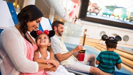 A mother in a lounge chair holds her young daughter while her husband and young son relax beside them