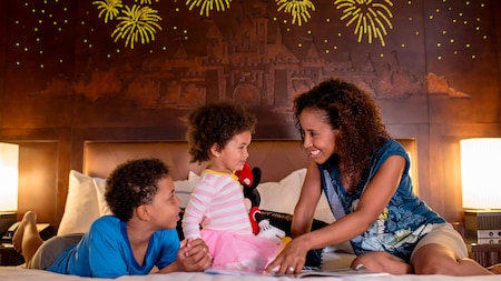 Una madre y sus 2 pequeños hijos comparten un momento feliz en su habitación de hotel