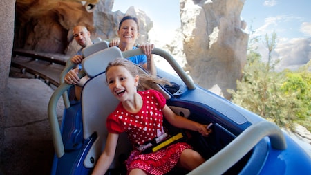 Una niña y sus padres pasean en vehículos para 3 personas de Matterhorn Bobsleds