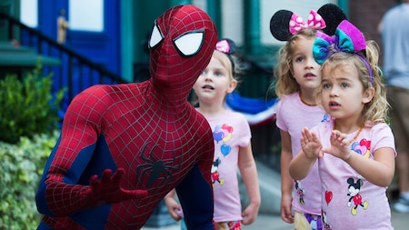 Spider Man strikes a kneeling action pose as 3 little girls look on