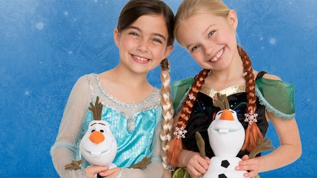 Two little girls, dressed as Anna and Elsa, each holding a plush Olaf toy
