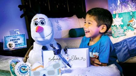 A boy looks at his Frozen gifts, including a plush Olaf and an autograph book signed by Anna and Elsa
