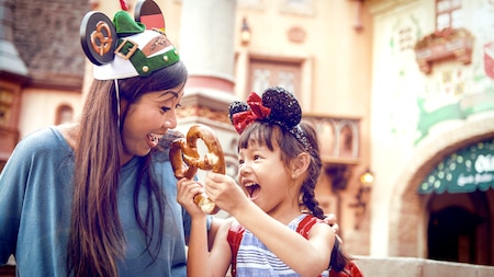 A woman laughs with a girl holding a pretzel