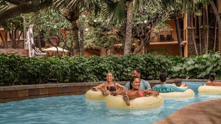 Guests sitting in inner tubes while floating through a lazy river at Aulani, A Disney Resort & Spa