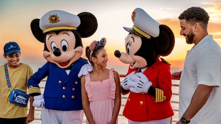 Capitão Mickey e Capitã Minnie cumprimentando um pai e seu filho e filha adolescentes no deck de um navio de cruzeiro