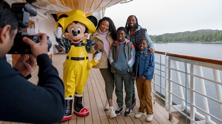Una familia de cuatro personas posa para una foto con Mickey Mouse, quien está vestido como un pescador