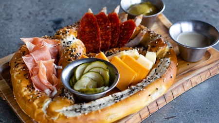 A charcuterie board with sliced meats, cheeses and sauce