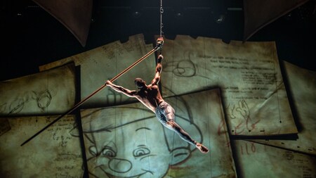 An aerial performer suspended in the air while holding an oversized pencil