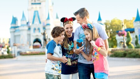 Cuatro miembros de una familia reunidos en torno a un teléfono móvil frente al Cinderella Castle