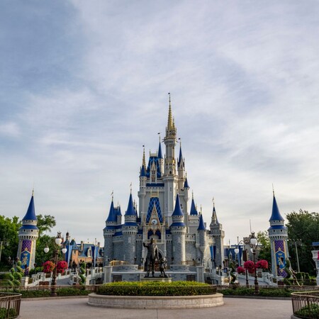 A statue of Walt Disney and Mickey Mouse in front of Cinderella Castle