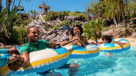Family members hold hands while floating in tubes at Disney’s Typhoon Lagoon water park