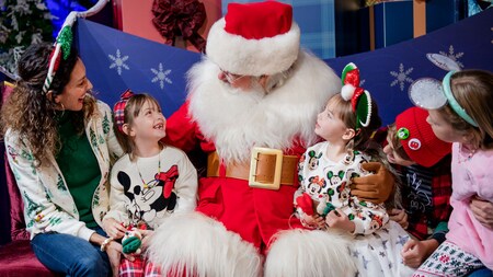 Cuatro niños y su madre sentados en un trineo con Santa Claus