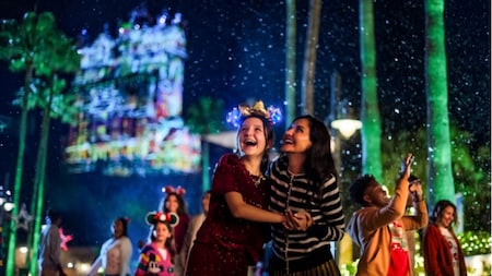 A mother and a daughter holding hands as they gaze at the night sky in Disney’s Hollywood Studios