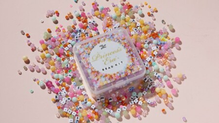 A container of colorful beads scattered on a blank surface