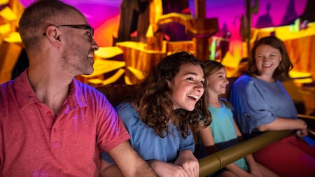 A father, mother and their 2 daughters riding Mickey & Minnie’s Runaway Railway